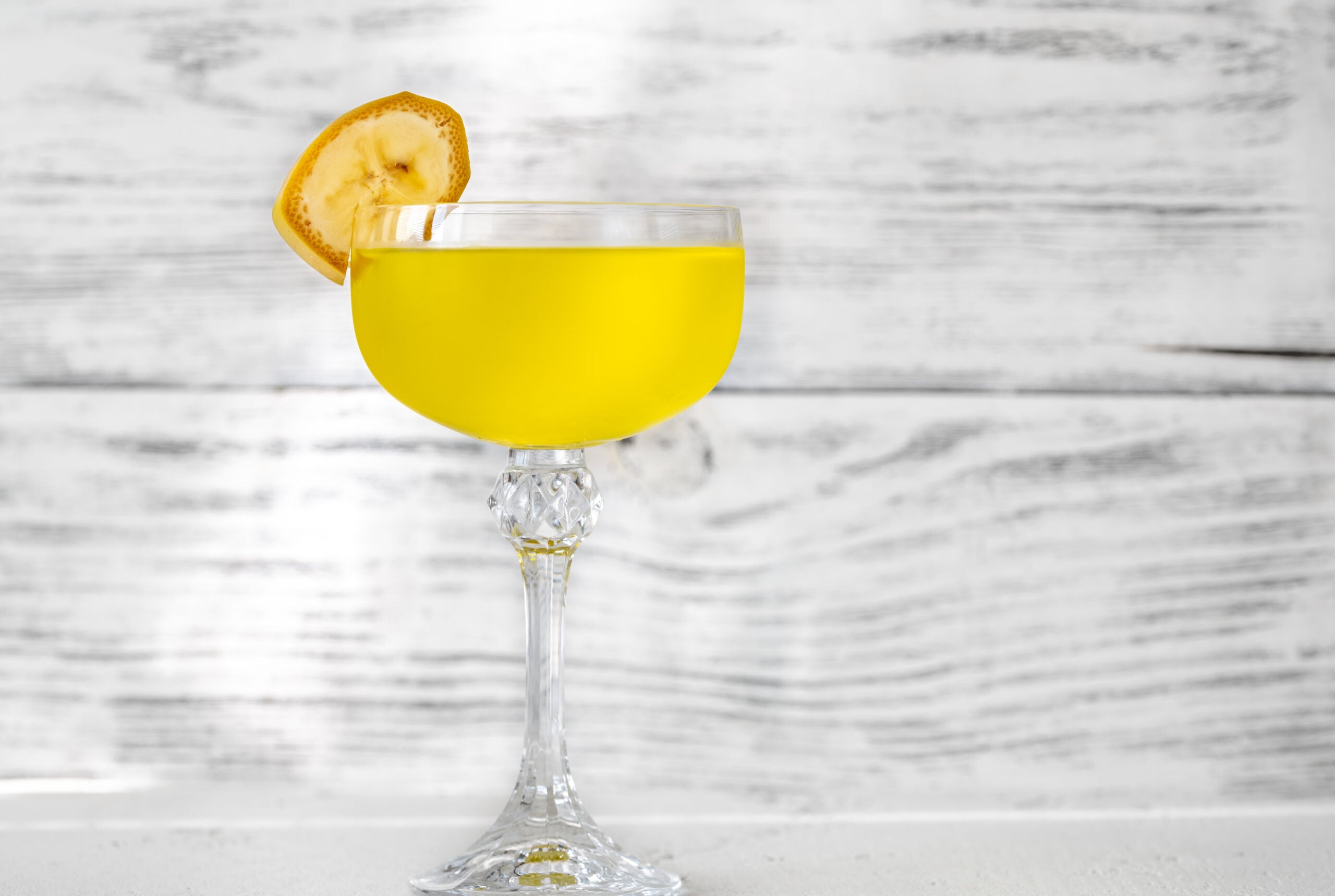 A grey wooden background showcasing a single Yellow Submarine cocktail. 