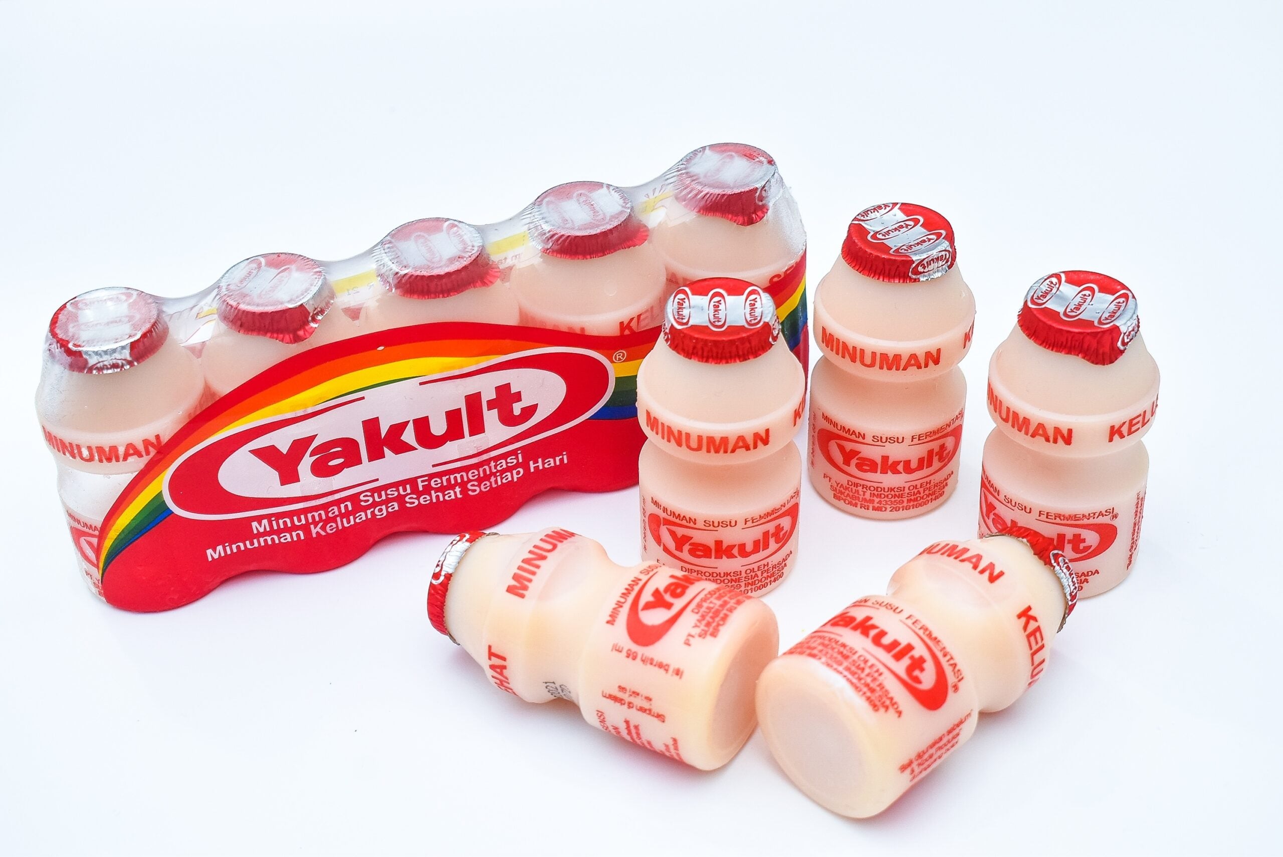 Several bottles of Yakult on a white background.
