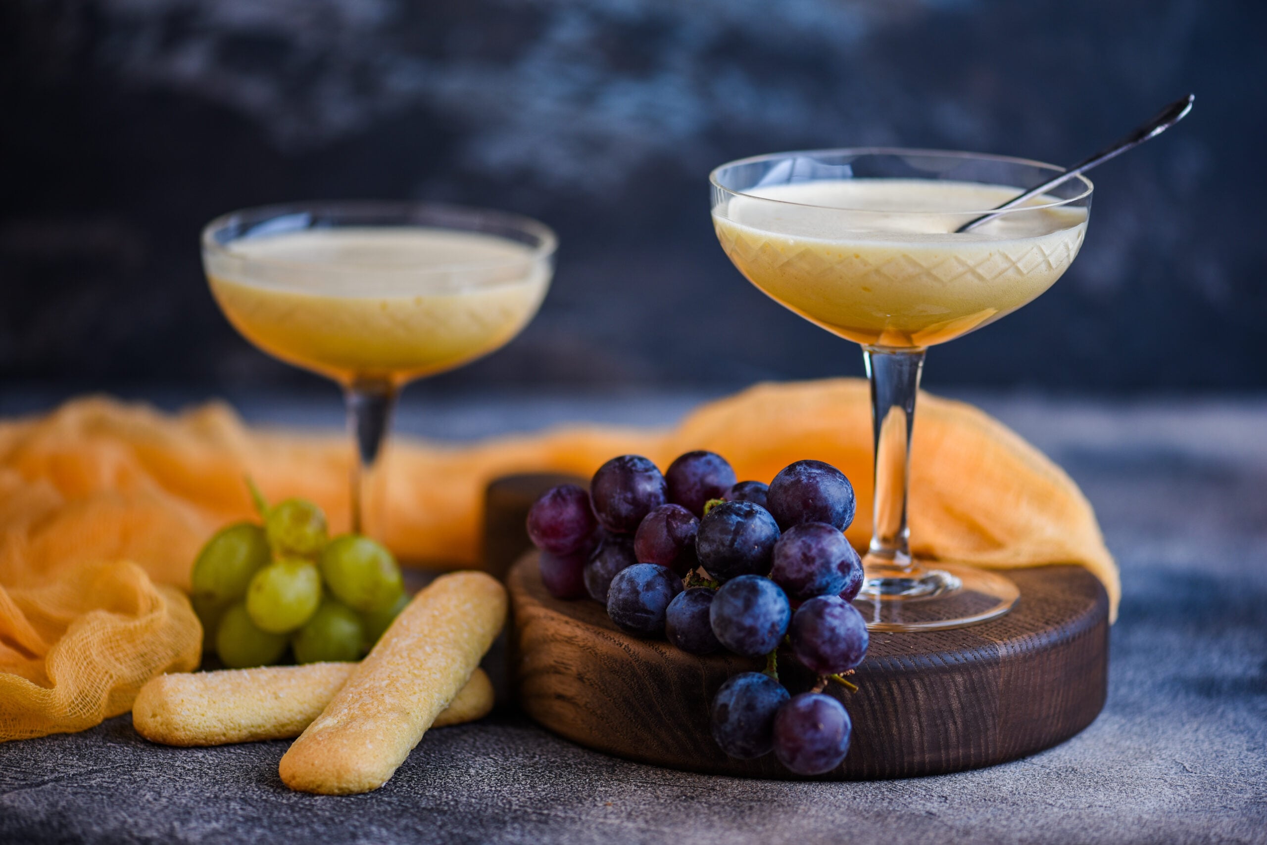 A concrete table featuring Italian zabaione cream and grapes. 