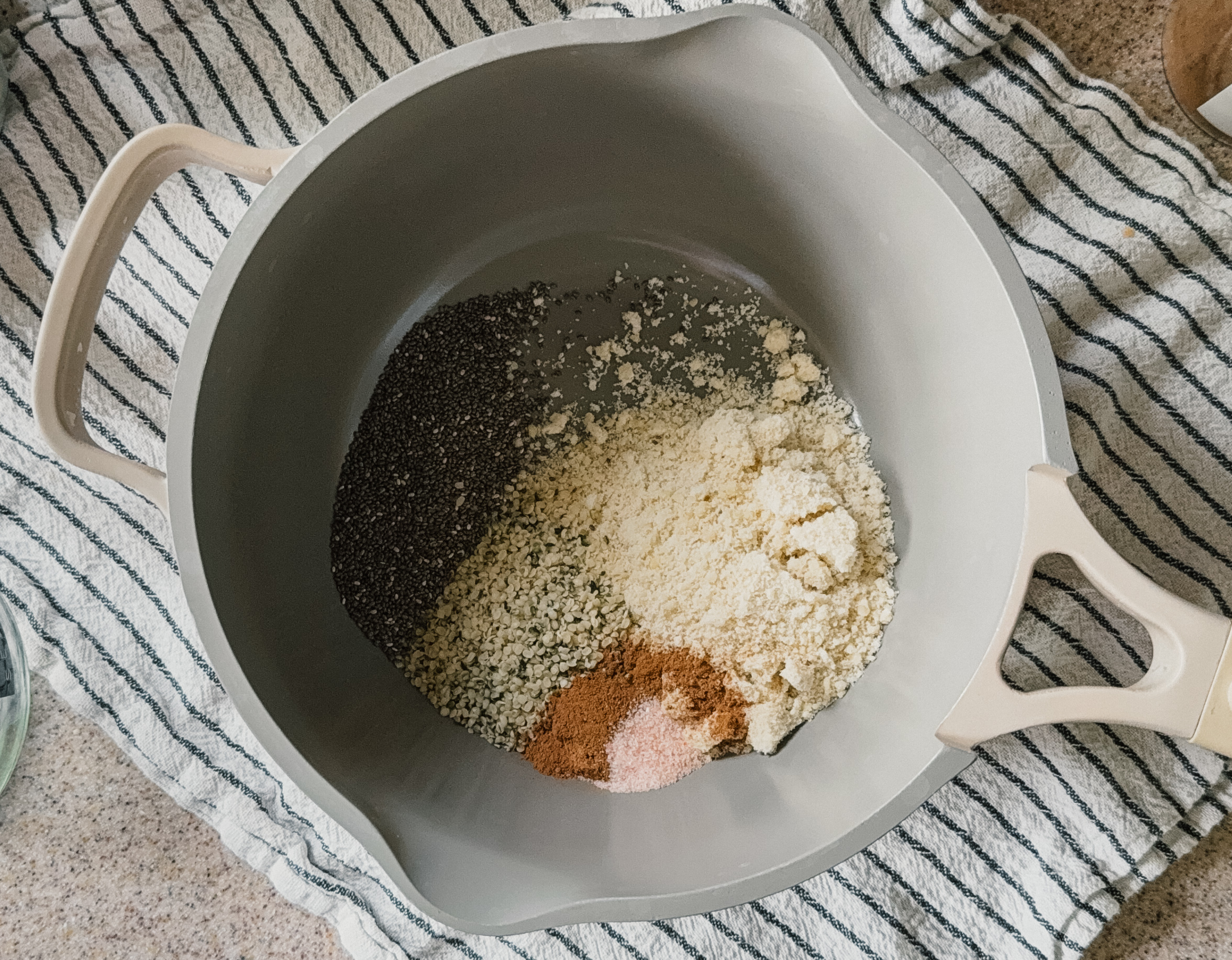 A pot of ingredients sitting on top of a striped tea towel.