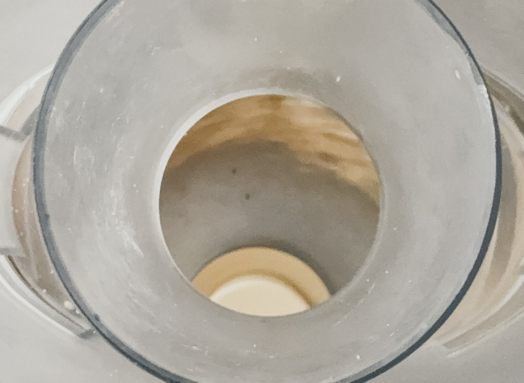 A image looking down into a food processor of peanuts being ground into peanut butter.