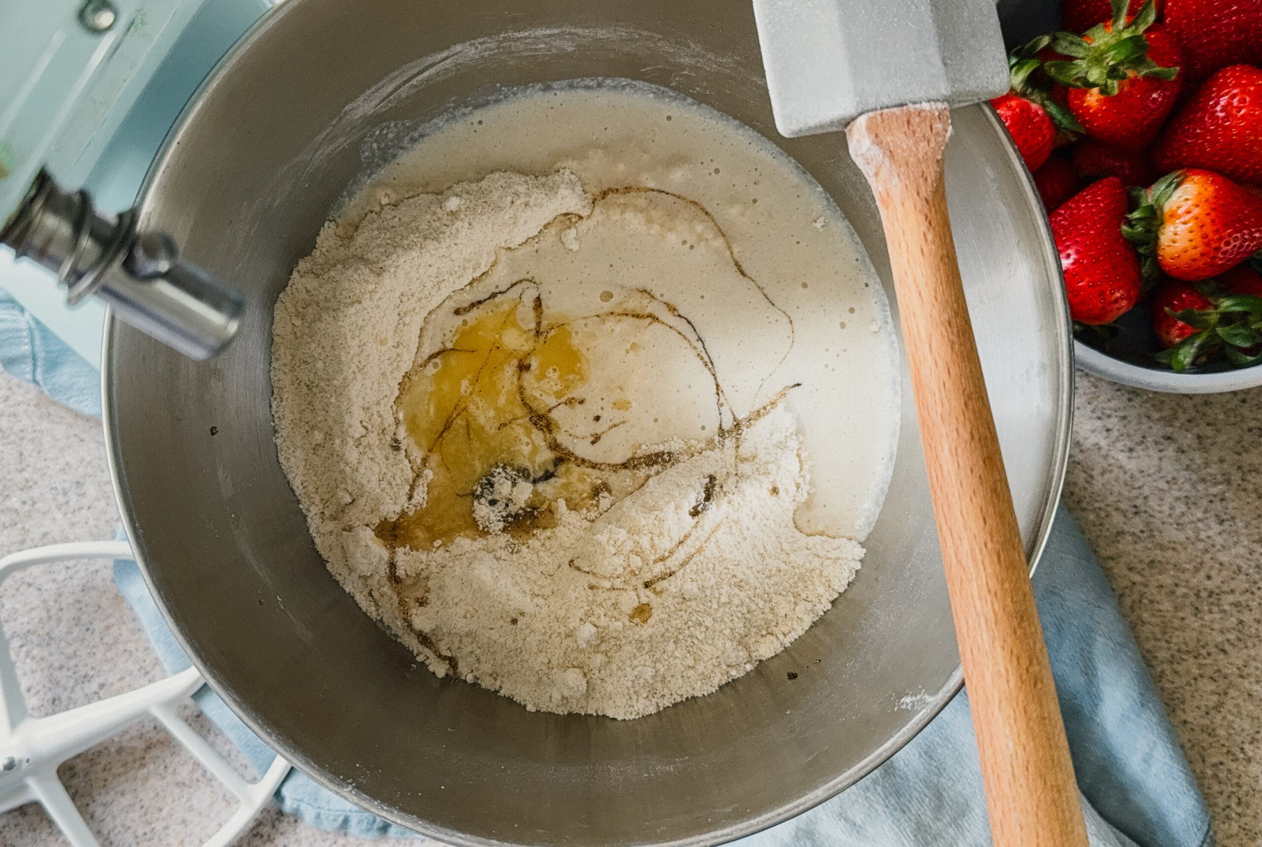 A mixer bowl full of ingredients. A spatula rests on the right side of the bowl.