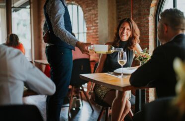 Couple on a date with a waiter pouring a drink.
