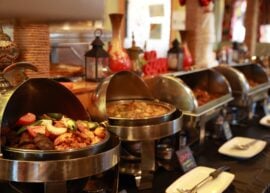 Buffet with open dishes on it, with middle eastern cookware behind