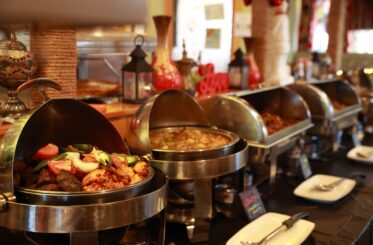 Buffet with open dishes on it, with middle eastern cookware behind
