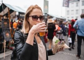 woman drinking a beer and eating a burger