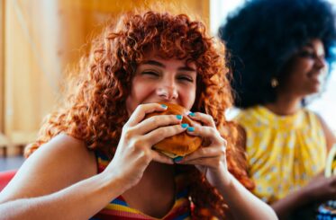 Woman eating a hamburger with friends