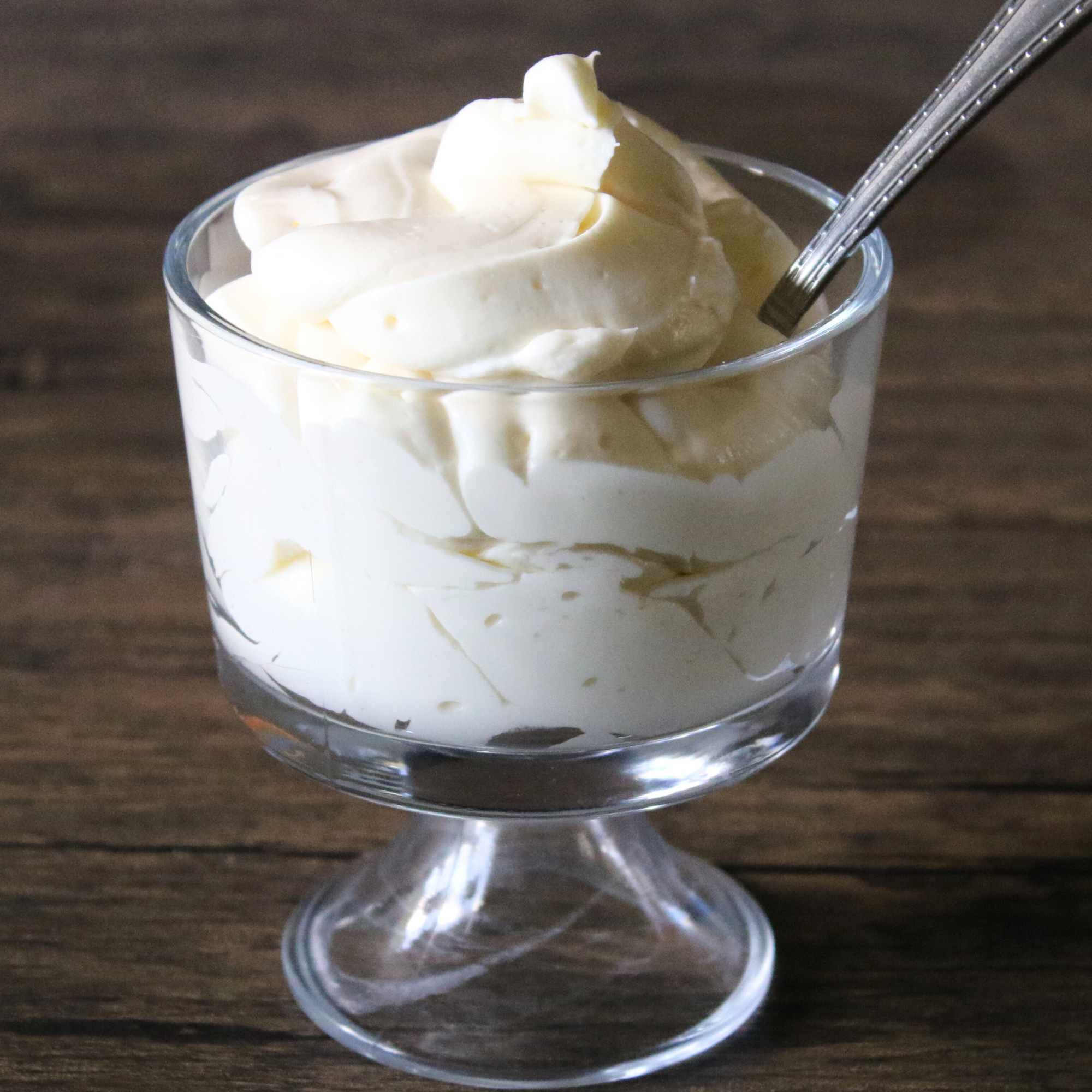 Whipped cheesecake fluff in a glass serving bowl on a wooden countertop.