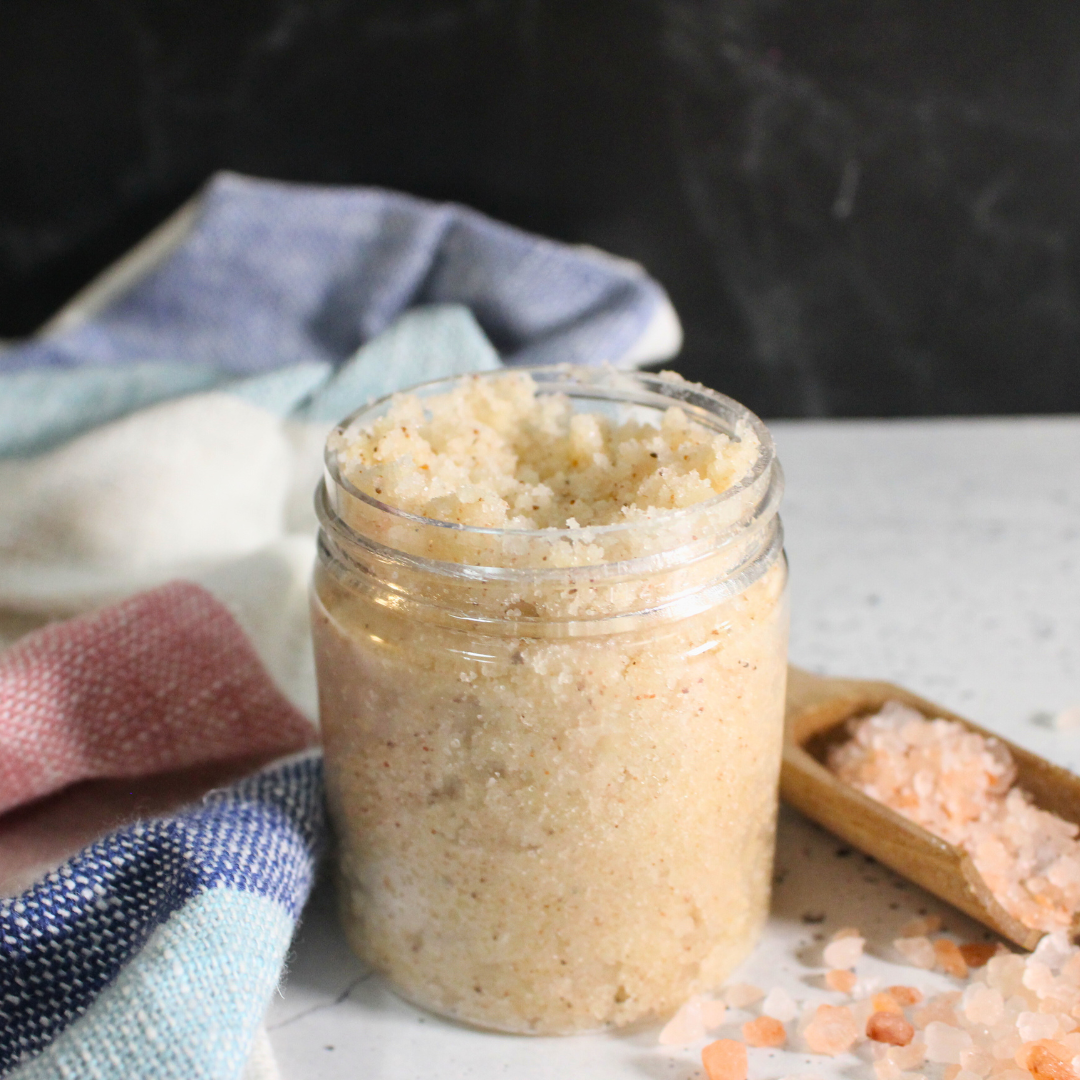 A salt scrub in a glass jar on a countertop.