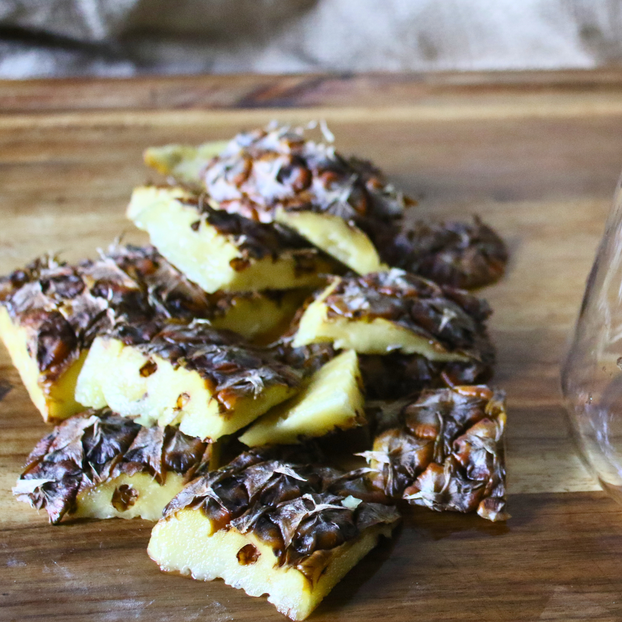Sliced pineapple skins on a wooden butcher block.
