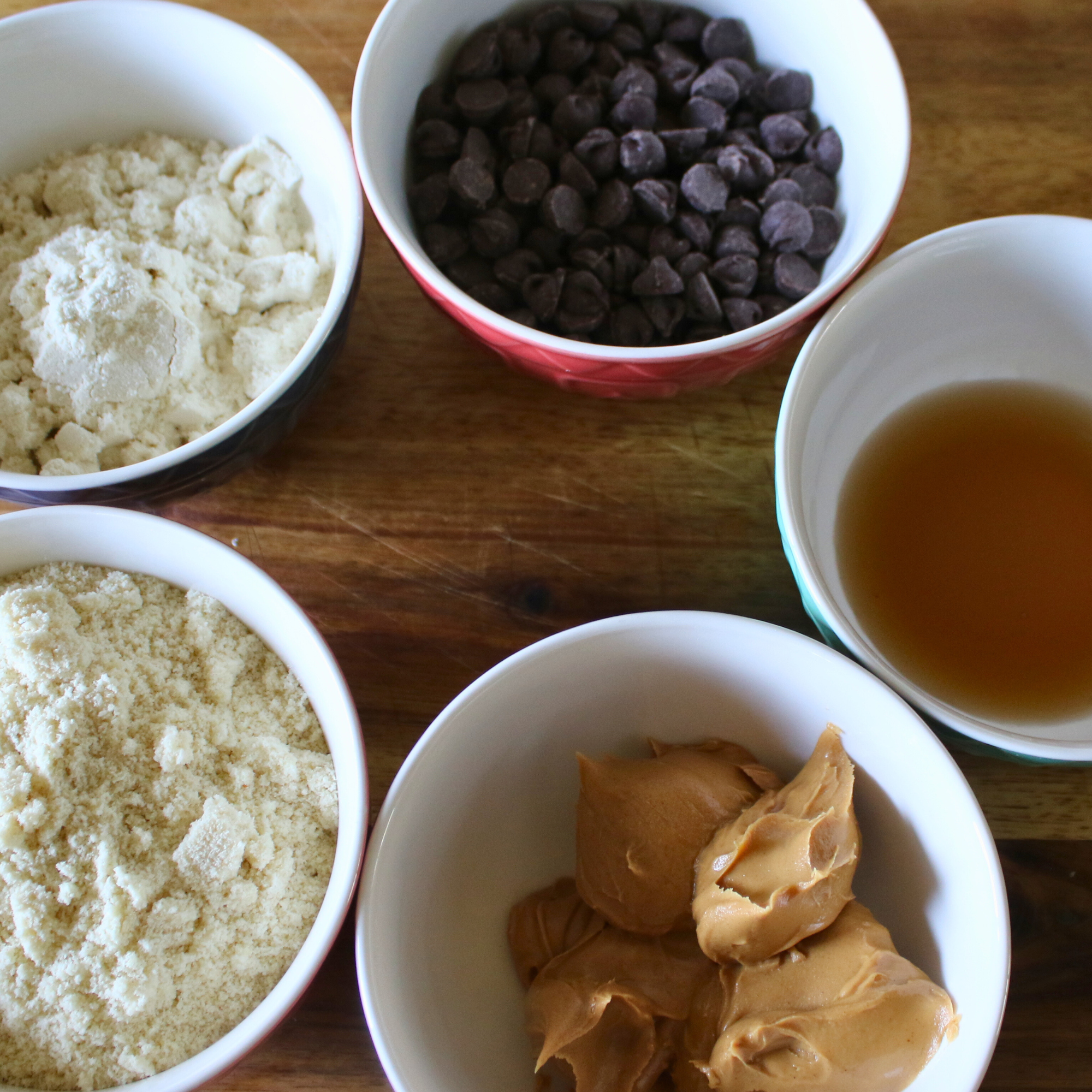 Five bowls full of ingredients to make protein cookie dough.