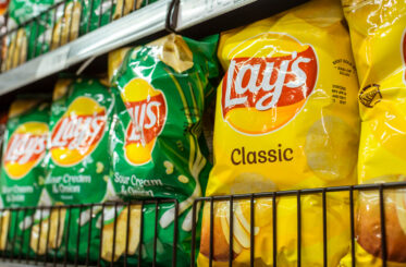 Bags of Lays chips on a store shelf, including Classic and Sour Cream & Onion flavors.