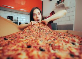 Woman grabbing a slice of a huge pizza