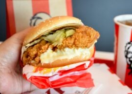 Hand holding a chicken sandwich with lettuce and mayonnaise.