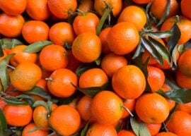 Pile of fresh oranges with green leaves attached.