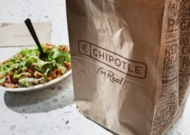 Brown Chipotle bag next to burrito bowl with vegetables.