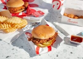 Fried chicken sandwich, waffle fries, nuggets, sauces, and drink on table.