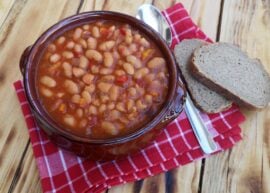 Baked beans in a bowl with two slices of bread next to it