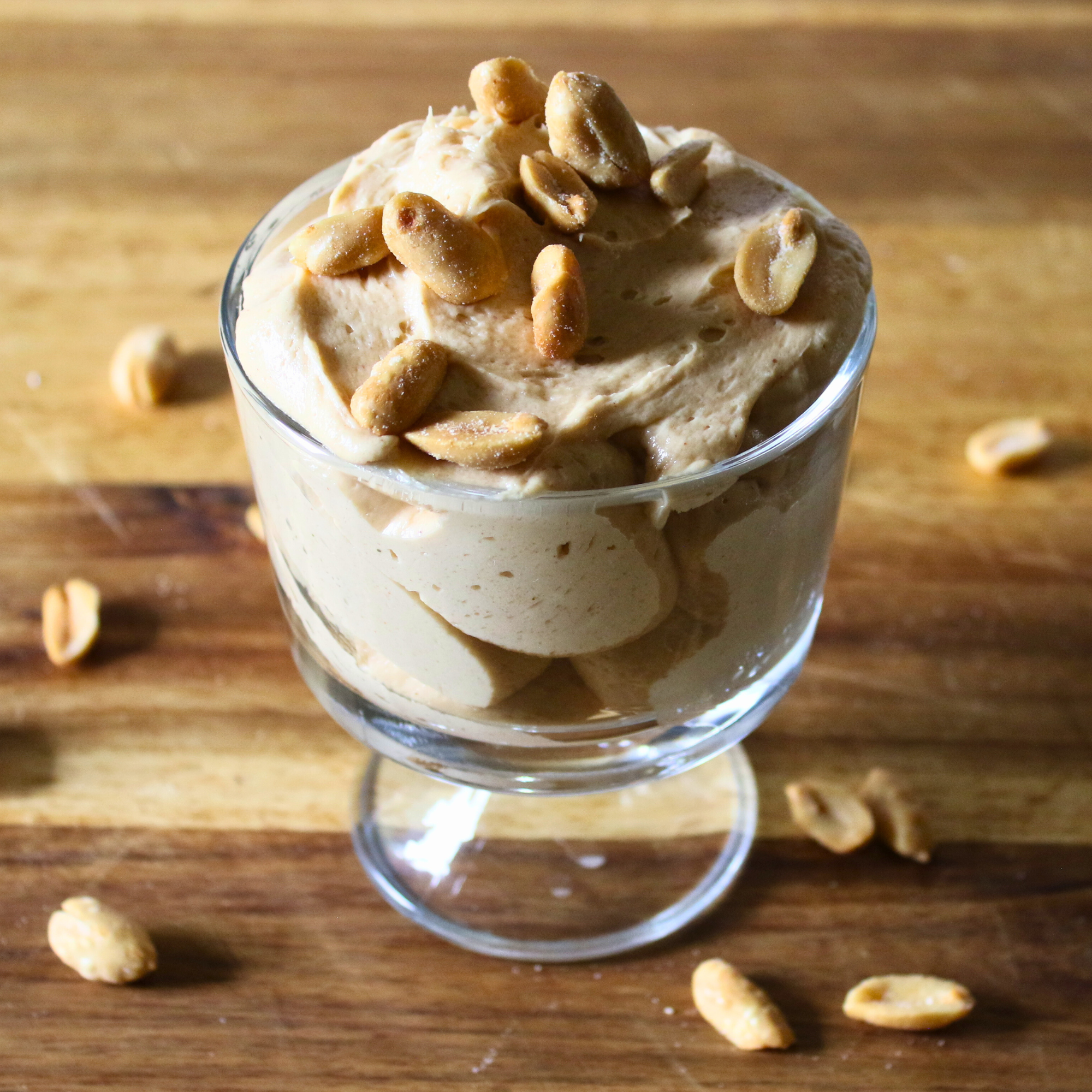 Whipped peanut butter mousse in a glass serving dish topped with peanuts.