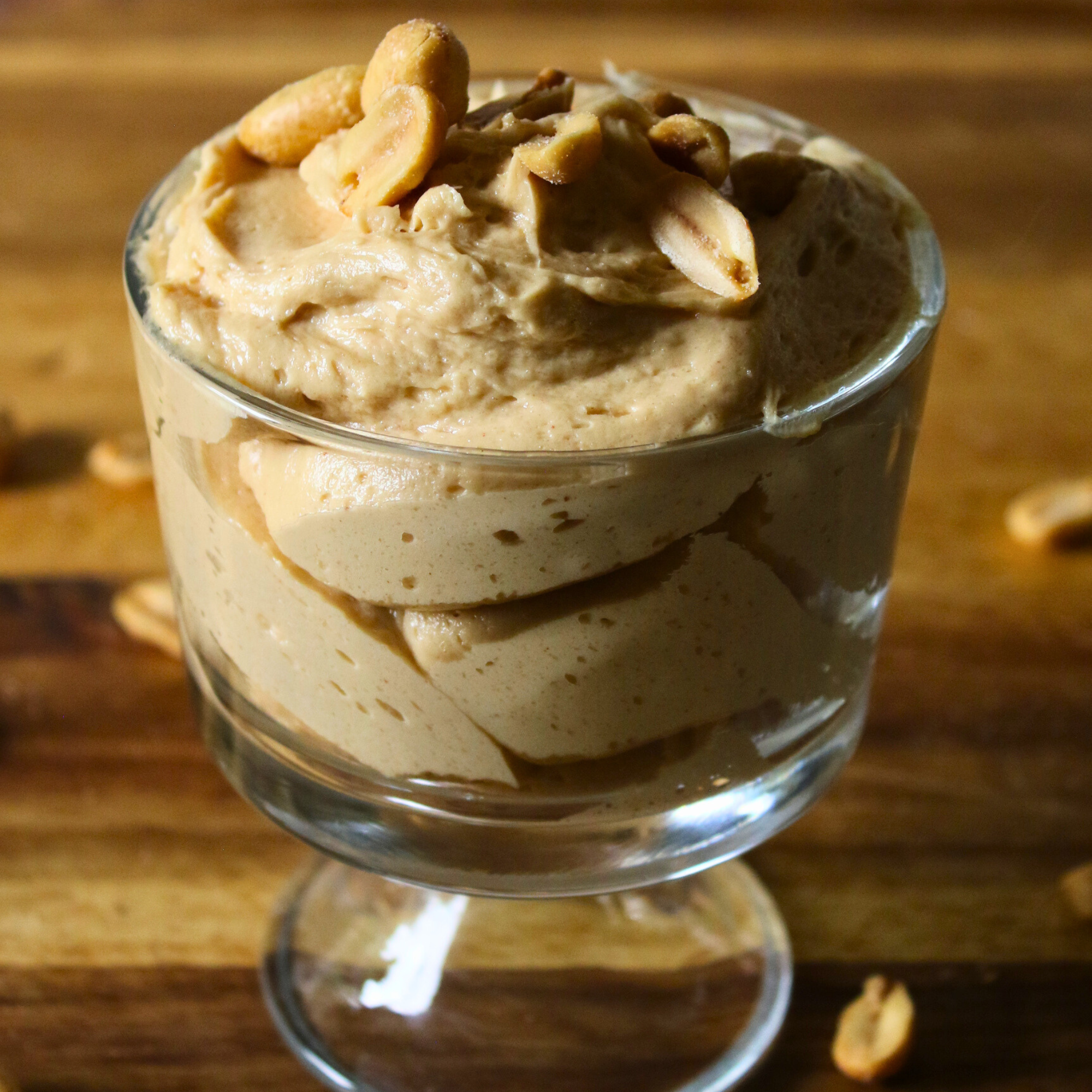 Whipped peanut butter mousse in a glass serving dish topped with peanuts.