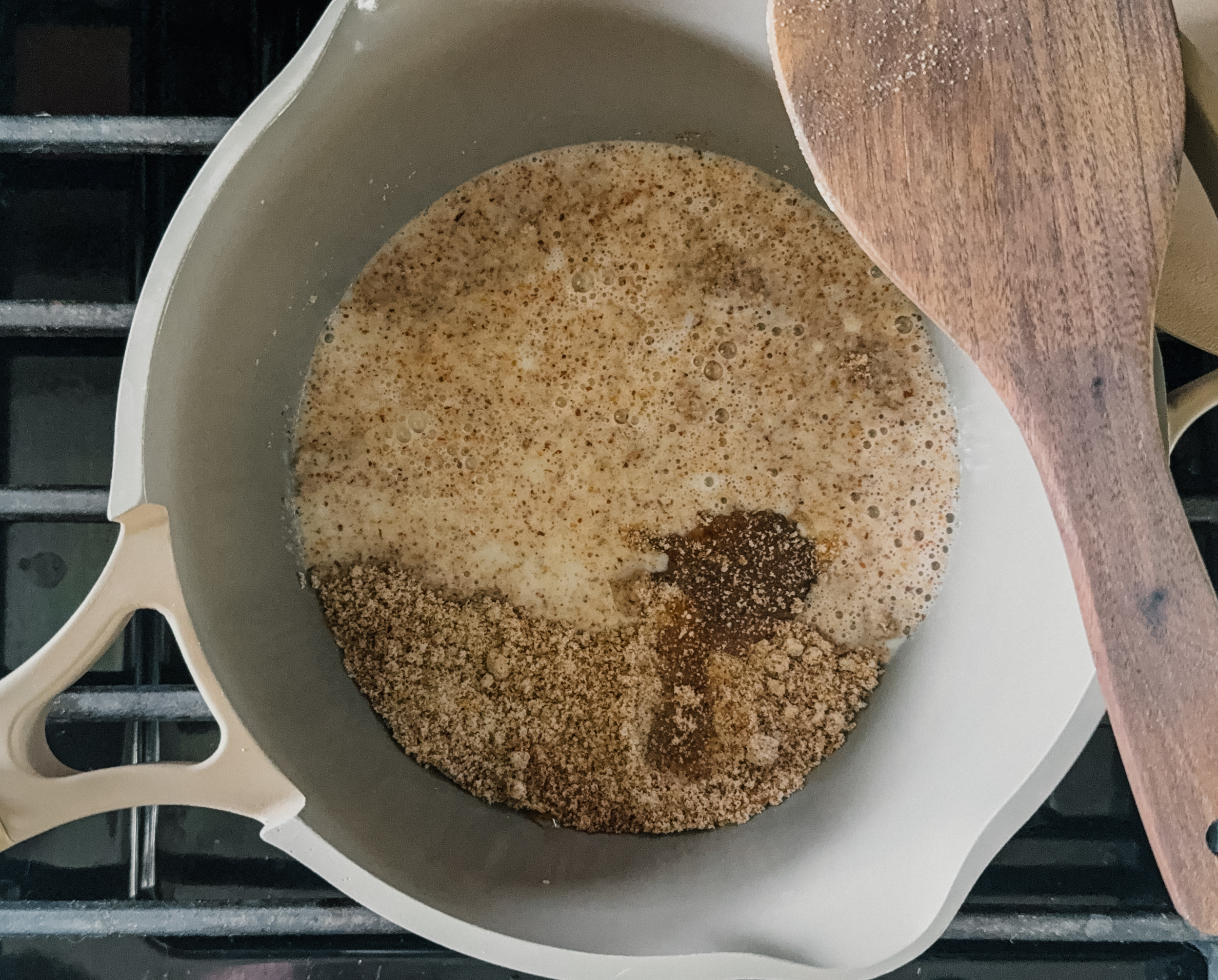 A pot full of ingredients for porridge. A wooden spoon rests on the upper right side of the pot.