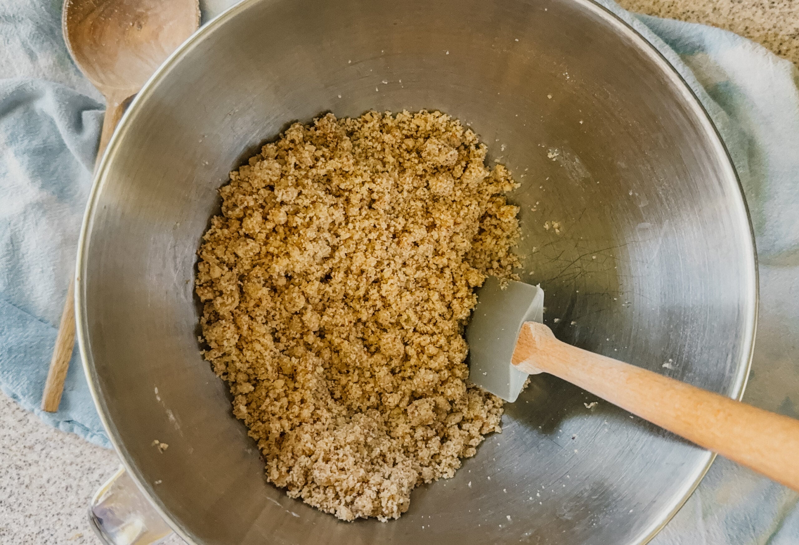 A silver bowl with pie crust ingredients being mixed. A spatula sticks out of the lower right side of the bowl.