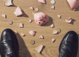 Businessman feet and broken piggy bank top view.