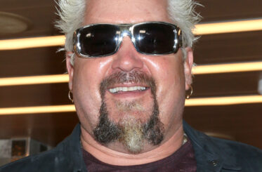 Guy Fieri smiling at the camera with glasses on