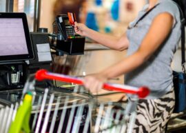 Woman with cart at self-checkout cardswipe