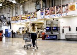 A shopper walking their shopping cart towards Costco's food court.