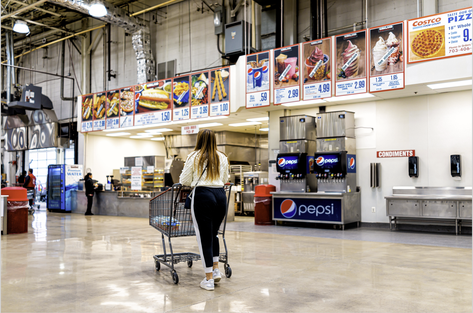 A shopper walking their shopping cart towards Costco's food court.