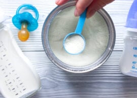 Powdered infant formula next to a pacifier and bottles
