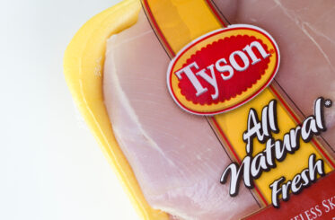 Closeup of American meat processing company Tyson Foods branded boneless skinless chicken thigh product isolated on a white background.