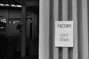 Factory Shut Down sign in front of the factory warehouse.