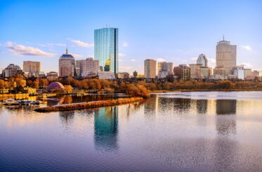 Boston City Skyline over the Charles River in Massachusetts, USA. A tranquil riverscape of Back Bay with golden illuminated wintery foliage in New England.