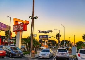 Vintage In-N-Out Burger restaurant with landing Delta Airlines aircraft near Los Angeles International Airport (LAX) during sunset.