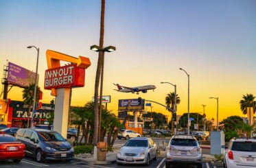 Vintage In-N-Out Burger restaurant with landing Delta Airlines aircraft near Los Angeles International Airport (LAX) during sunset.