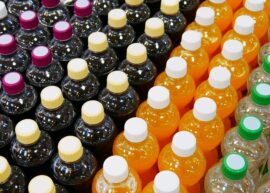 Many plastic bottles of different drinks with multi-colored caps standing in rows