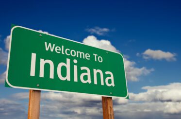 Welcome To Indiana Green Road Sign Over Blue Sky with Some Clouds.