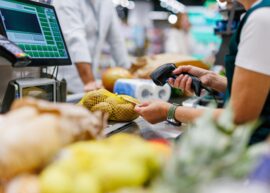 Supermarket cashier scanning potatoes at the checkout counter, processing groceries for a customer during a busy shopping day