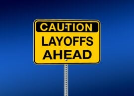 Caution Layoffs Ahead sign with a blue background