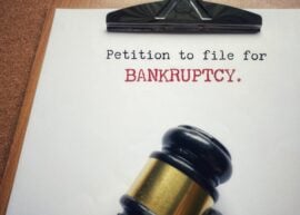 Clipboard with paper reading 'petition to file for bankruptcy" with a judge's gavel