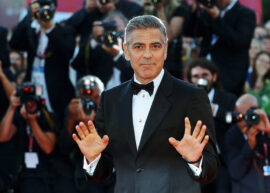 George Clooney in a tuxedo with his hands up.
