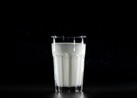 A glass of fresh milk against a black background, emphasizing simplicity and nutrition.