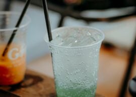 Chilled green soda with ice in a plastic cup, perfect for a refreshing outdoor drink.