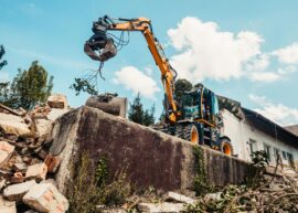 A bulldozer efficiently demolishing an old building, clearing rubble.