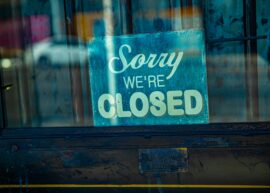 Retro 'Sorry We're Closed' sign displayed on a rustic glass door, depicting temporary closure.
