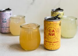 Vibrant display of cannabis-infused drinks in cans and glasses, featuring Blood Orange Cardamom flavor.