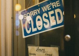 Close-up of a store's closed sign and business hours displayed on the door.