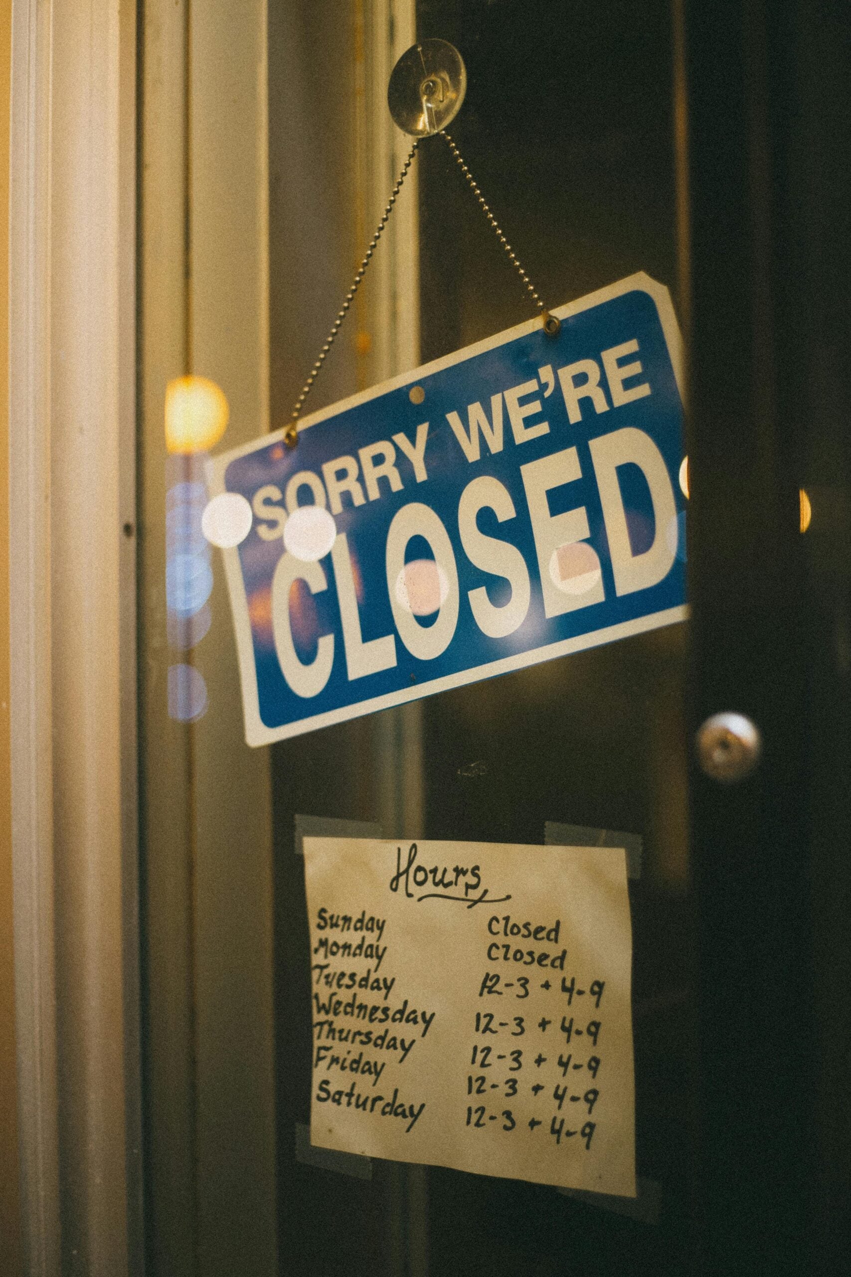Close-up of a store's closed sign and business hours displayed on the door.